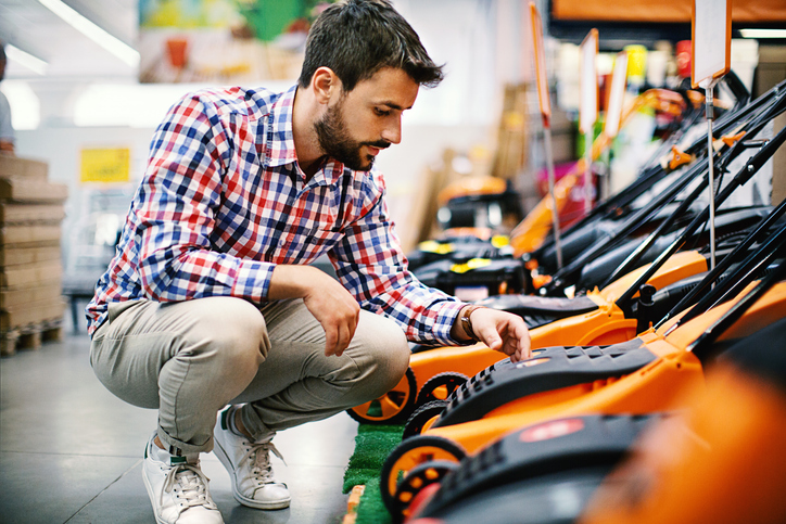 Image on a man looking at lawn mowers unsure which one to buy.